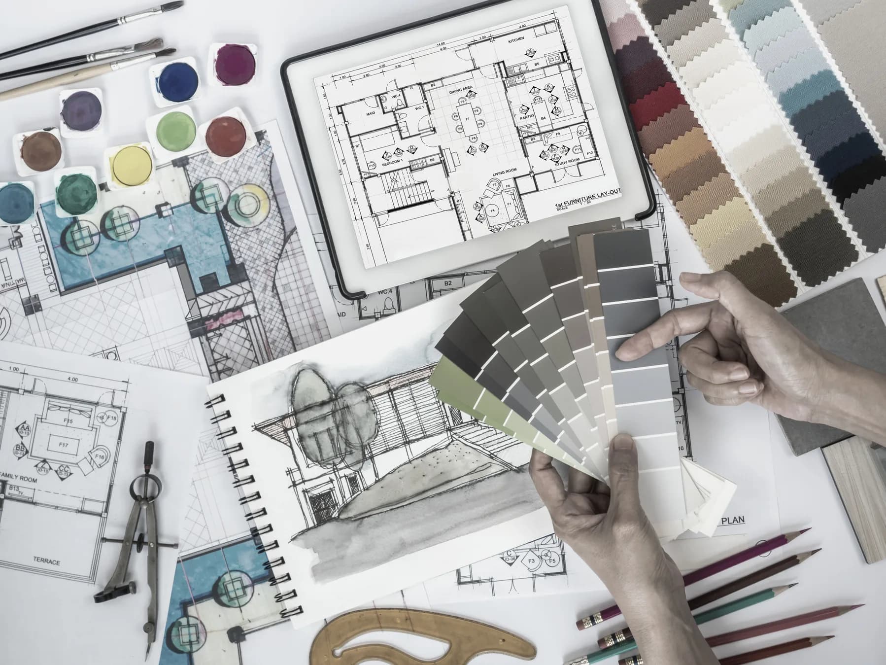 Interior design workspace with drawings, material palettes, and fabric samples